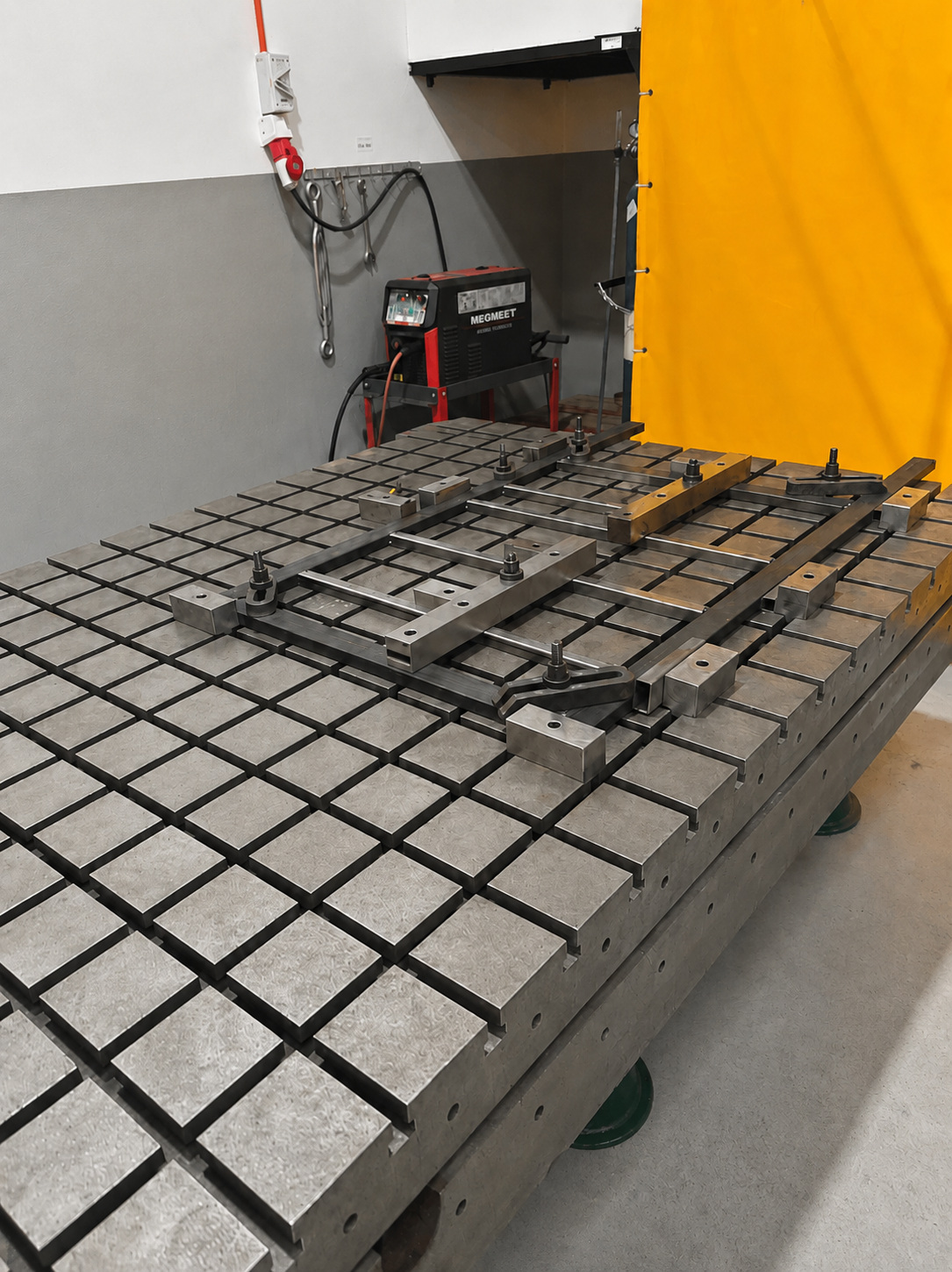 Metal frame components clamped on a slotted welding table